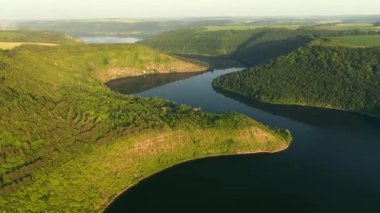 Yeşil tepelerden akan kıvrımlı nehrin panoramik manzarası kuş bakışı. UHD 4k video ile çekildi.