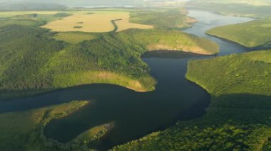 Yeşil tepelerden akan kıvrımlı nehrin panoramik manzarası kuş bakışı. UHD 4k video ile çekildi.