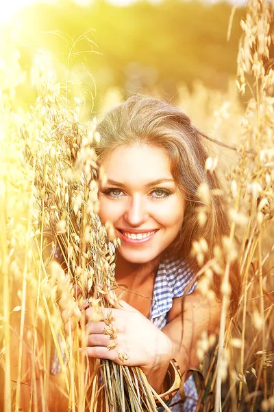 Unga leende kvinna i vit klänning stående i fältet — Stockfoto