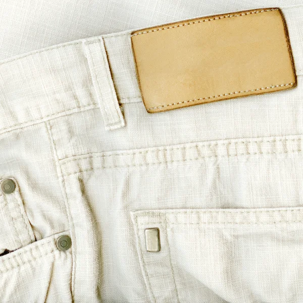 Fragment of white jeans with pure label for your text. — Stock Photo, Image