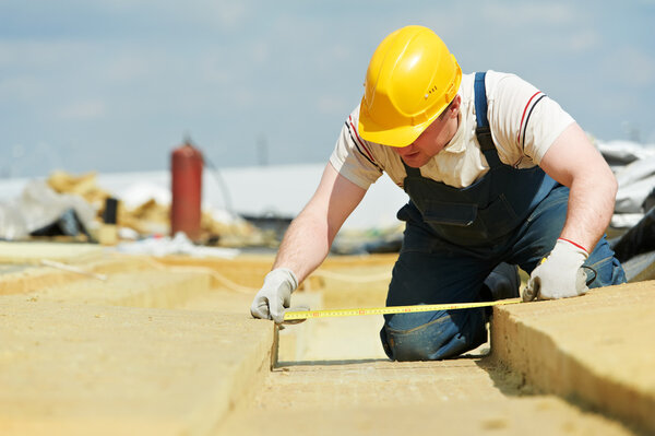 Roofer worker measuring insulation material