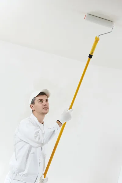 Pintor de casa no trabalho com rolo de pintura — Fotografia de Stock