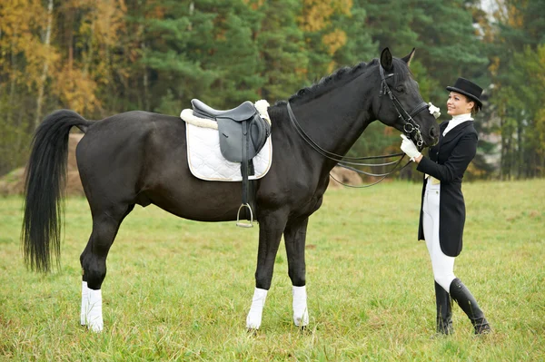 Žokej žena v uniformě s koněm — Stock fotografie