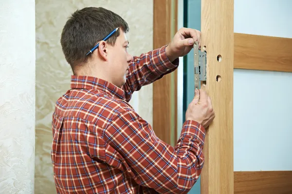 Carpenter at door lock installation — Stock Photo, Image