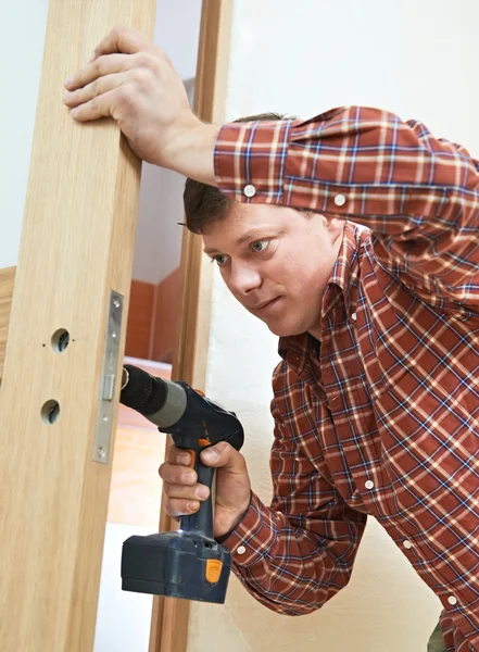 Carpenter at door lock installation — Stock Photo, Image