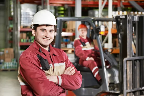 Trabajador de almacén frente a carretilla elevadora — Foto de Stock