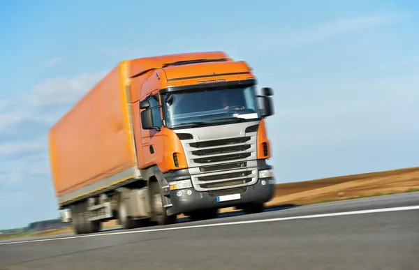 Oranje vrachtwagen aanhangwagen over blauwe hemel — Stockfoto
