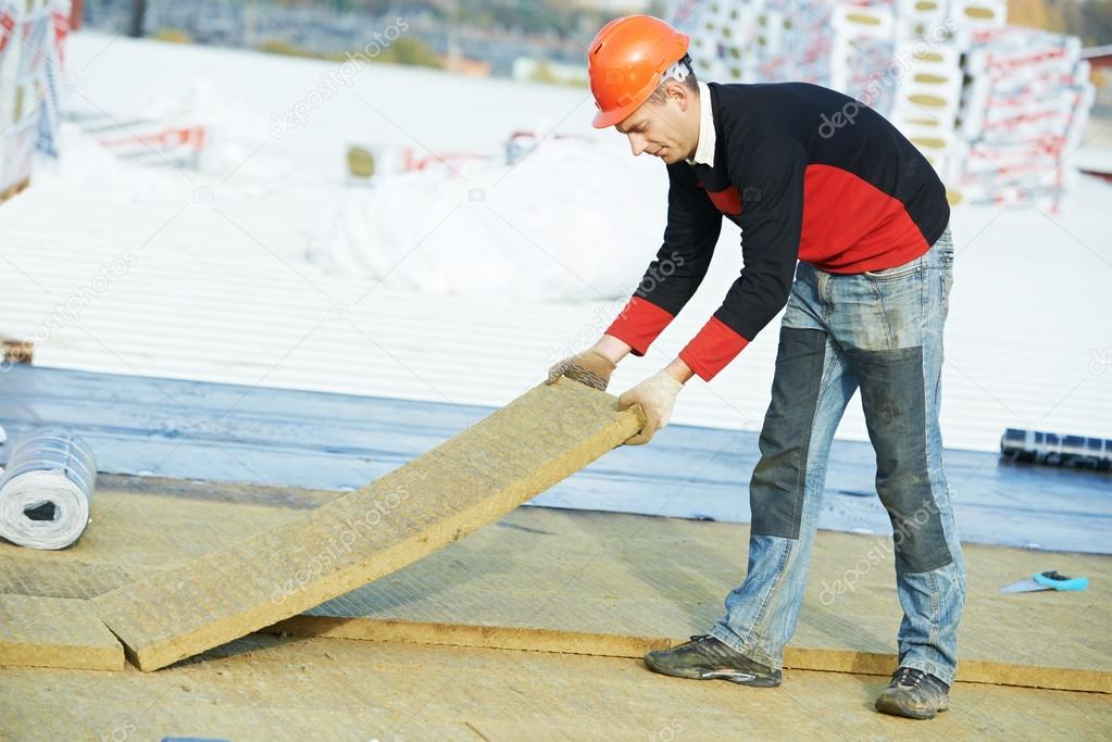Roofer worker installing roof insulation material