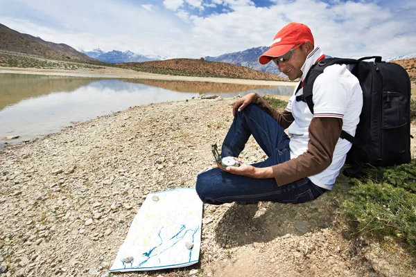 Tourist hiker with compass and map in mountains — Stock Photo, Image