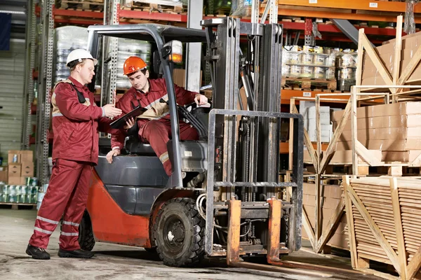 Warehouse workers in front of forklift — Stock Photo, Image