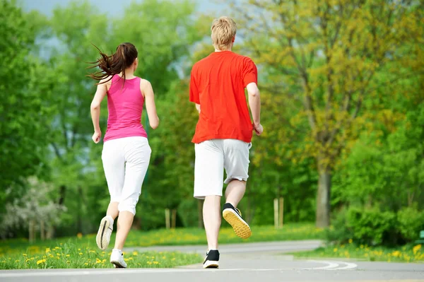 Joven hombre y mujer corriendo al aire libre — Foto de Stock