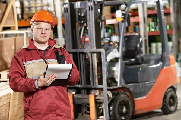 Warehouse worker in front of forklift — Stock Photo, Image