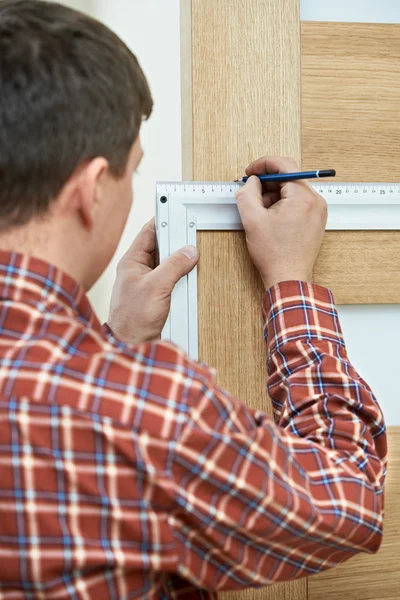 Timmerman tijdens de installatie van de deur — Stockfoto