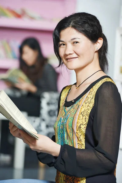 Jovem estudante chinês menina com livro na biblioteca — Fotografia de Stock