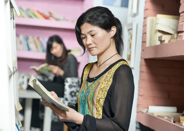Молодий китайський школяр дівчина з книгою в бібліотеці — стокове фото