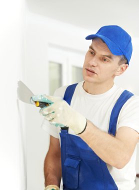 Plasterer with putty knife at wall filling clipart