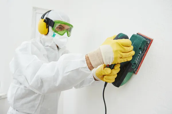 Werknemer met sander op muur vullen — Stockfoto