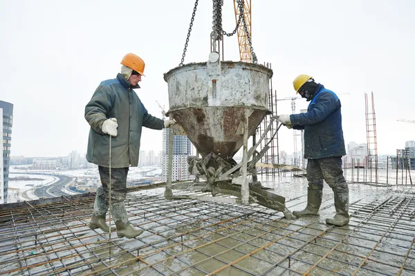 Trabajadores de la construcción vertiendo hormigón en forma — Foto de Stock