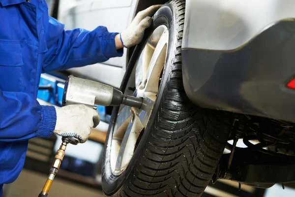 Auto mechanic screwing car wheel by wrench — Stock Photo, Image