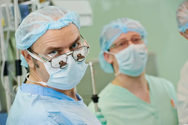 Equipe de cirurgiões sorridentes na cirurgia cardíaca — Fotografia de Stock