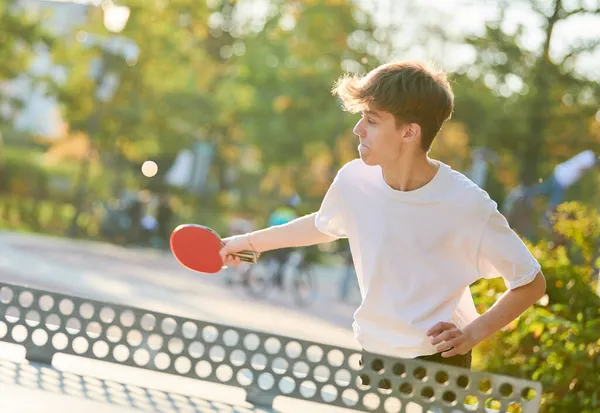 Мальчик играет в настольный теннис пинг-понг на открытом воздухе — стоковое фото