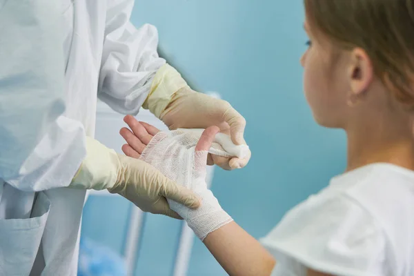 Surgeon doctor bandaging childs hand in clinic — Stock Photo, Image