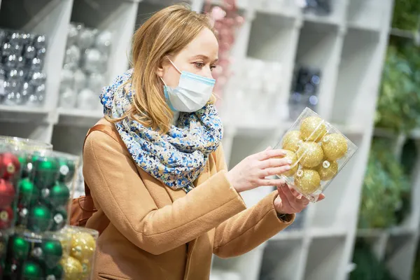 Decorazioni natalizie shopping. donna in maschera acquistare arredamento nuovo anno nel negozio — Foto Stock