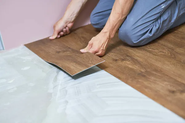 Trabajador uniéndose a revestimiento de suelo de vinilo en la renovación del hogar — Foto de Stock