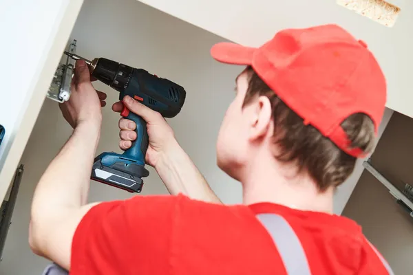 Assemblaggio mobili. Operaio professionista che installa armadio in soggiorno di nuova casa. — Foto Stock