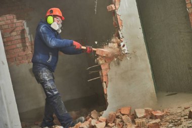 Yıkım işleri ve yeniden düzenleme. Balyozlu işçi duvarı yıkıyor.