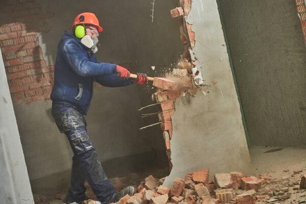 demolition work and rearrangement. worker with sledgehammer destroying wall