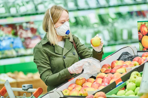 Žena v masce a ochranné rukavice nákup potravin v obchodě na koronavirus epidemie — Stock fotografie