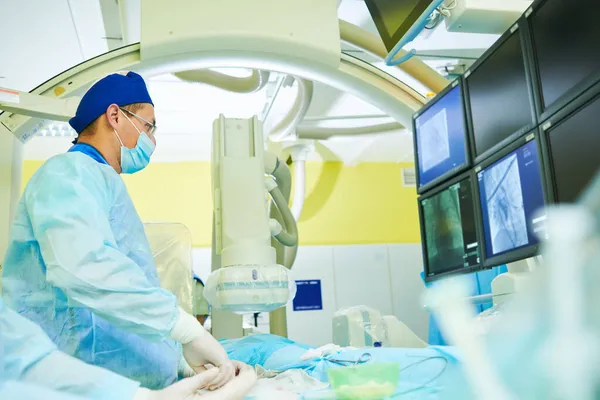 Radiología intervencionista. radiólogo cirujano en operación durante el tratamiento basado en catéter con visualización de rayos X. — Foto de Stock
