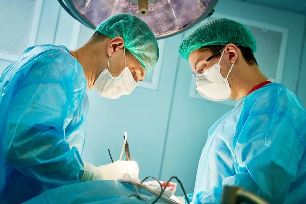 Cirurgia de emergência. Cirurgiões durante intervenção cirúrgica na clínica — Fotografia de Stock