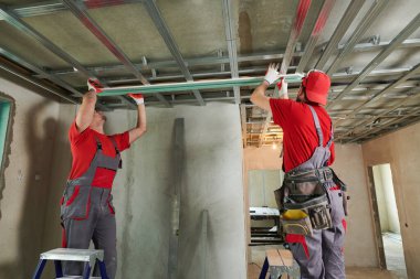 Alçıtaşı alçıpan işi. Evde alçıpan inşaatı var. Müteahhit işçi tavana metal çerçeve kuruyor