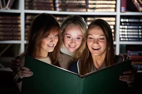 Young students reading magic book in library — Fotografia de Stock