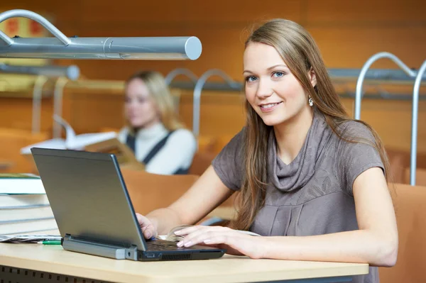 Young student girl working with laptop in library — Stockfoto