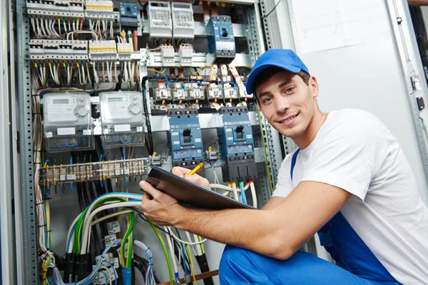 Electrician worker inspecting equipment and electricity meter — Stockfoto