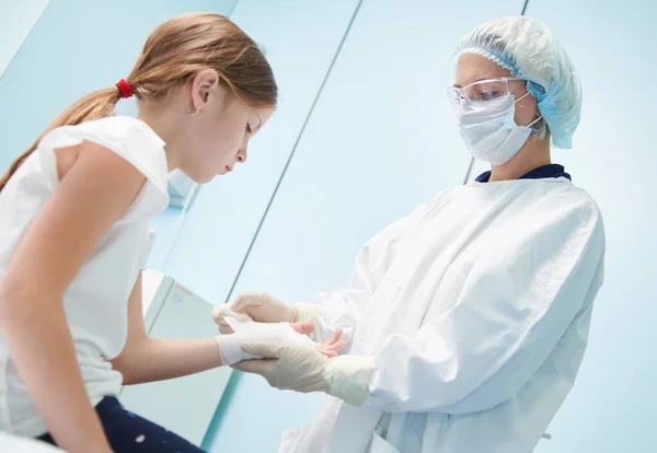 Médico cirujano femenino, en foco, vendaje de niños mano en la clínica —  Fotos de Stock