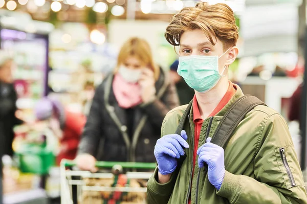 Человек в маске и защитных перчатках покупает в магазине во время эпидемии коронавируса — стоковое фото