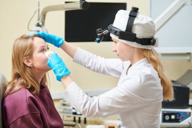 Kulak, burun, boğaz. Yetişkin bir hastanın kadın doktoru ya da KBB uzmanı. Otolarengoloji. Kadının burnunu inceliyorum.