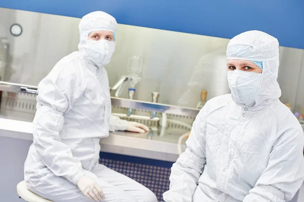 Microbilogy 研究所で危険危険ウイルス物質取り扱い保護制服の女性科学研究者および装置 — ストック写真
