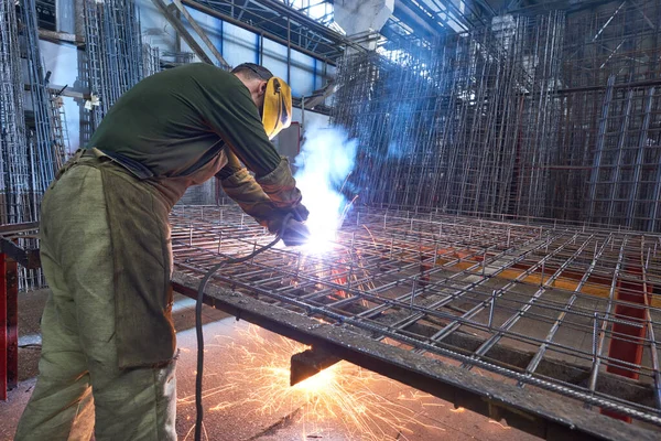 工場の工場で火花を散らしアーク溶接の工業用溶接工 コンクリート用労働者溶接補強格子 — ストック写真