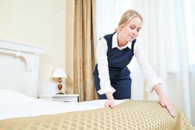 Otel Servisi. kadın ev işçisi hizmetçi ile yatak örtüsü ya da keten Inn Oda, yatak yapma