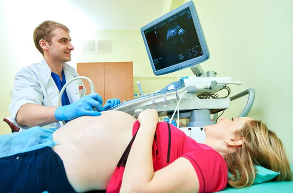 Ultrasound test. Pregnancy. Male gynecologist doctor checking patients fetal life signs with scanner.