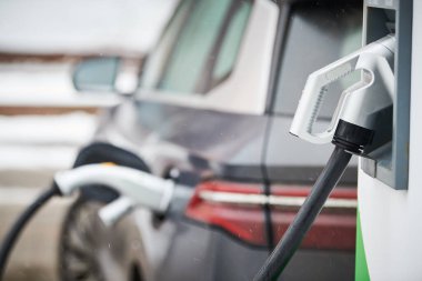 Elektrikli araba şarjı. Elektrik tedarik istasyonundaki elektrikli otomobilin şarj bağlantısı takıldı. Çevre dostu ulaşım