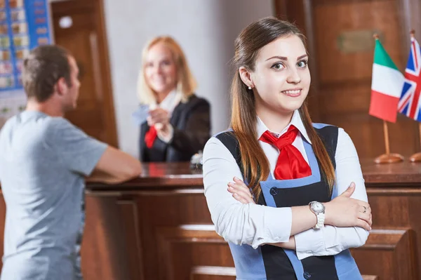ホテルフロント前で笑顔の若い女性受付マネージャー労働者 — ストック写真