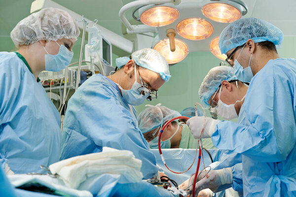 Команда хирурга в форме проводит операцию на пациенте в кардиохирургической клинике. Аутентичная стрельба в сложных условиях
