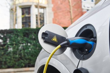 Elektrikli araba şarjı. Elektrik tedarik istasyonundaki elektrikli otomobilin şarj bağlantısı takıldı. Çevre dostu ulaşım
