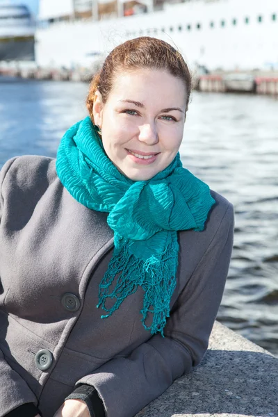 Vrouw in jas staande op stad embankment met cruise schip op achtergrond — Stockfoto